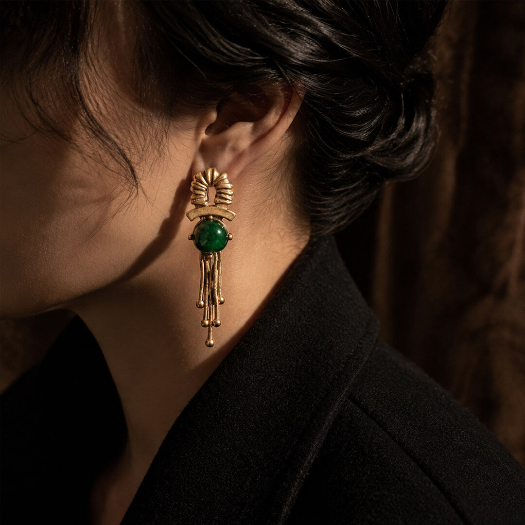 Vintage-inspired gold statement earrings styled with a black coat