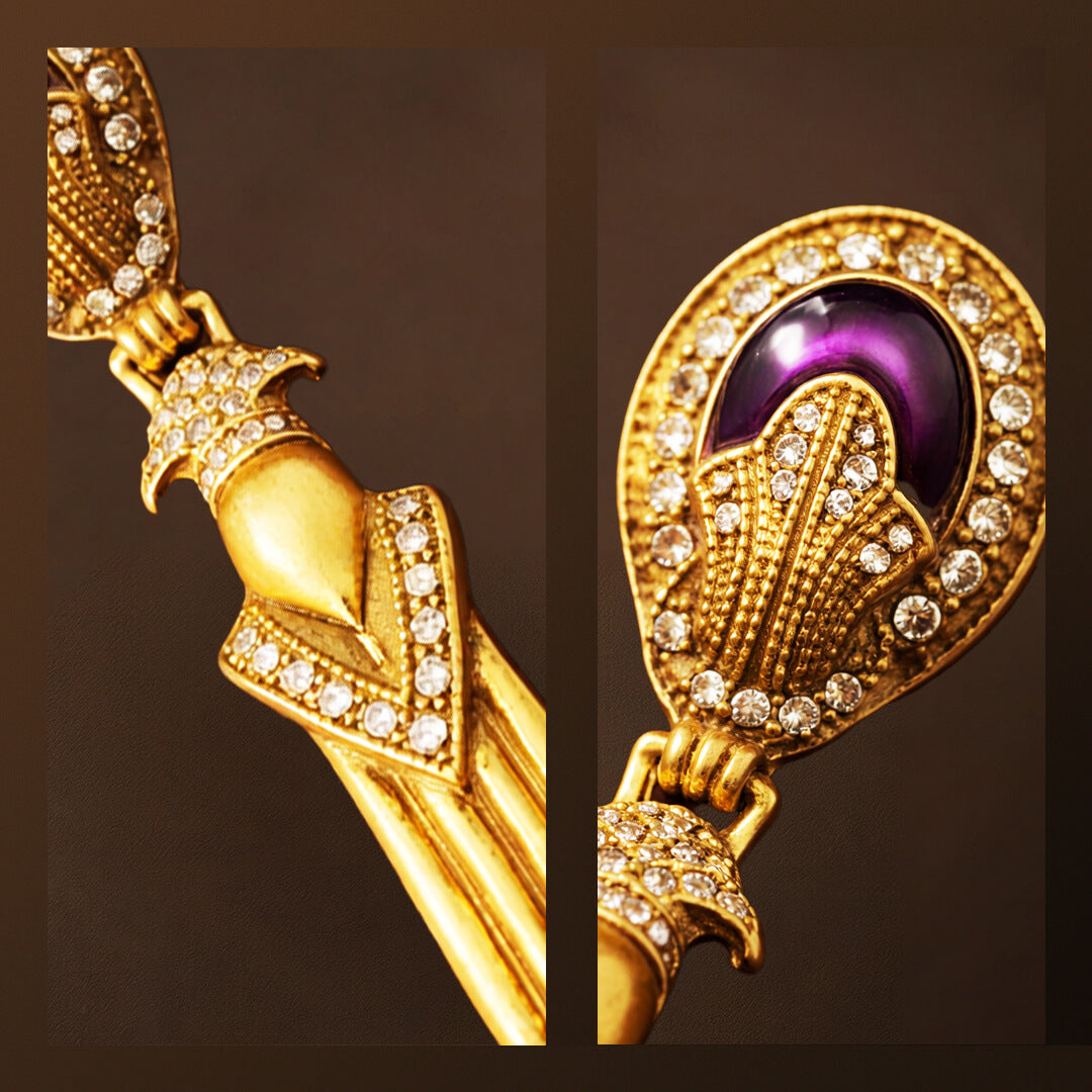 Close-up macro details of clear crystal pave and deep purple cabochon on vintage-style gold earrings.