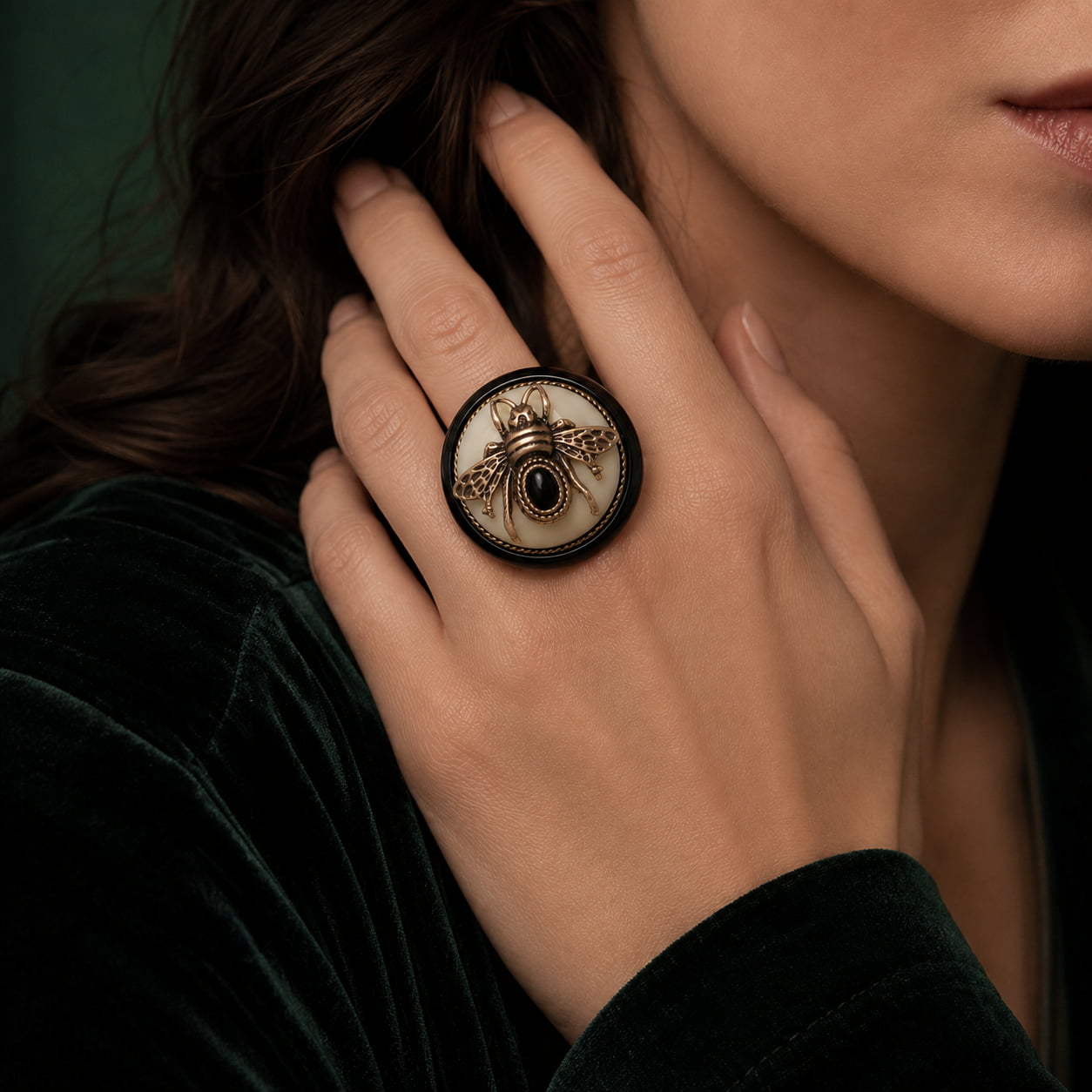 Close-up model view of a Retro Style bee cameo statement ring worn with dark green velvet.