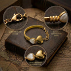 Macro details of the retro style lobster clasp, bangle connector, and pearl heart charms.
