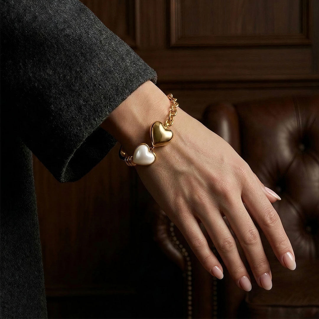 Close up of a vintage-inspired twin hearts bracelet resting on the wrist against a leather sofa.