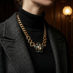 Alt Text: Close-up of a woman in a black turtleneck wearing a substantial vintage-inspired gold chain necklace featuring dark blue crystals.