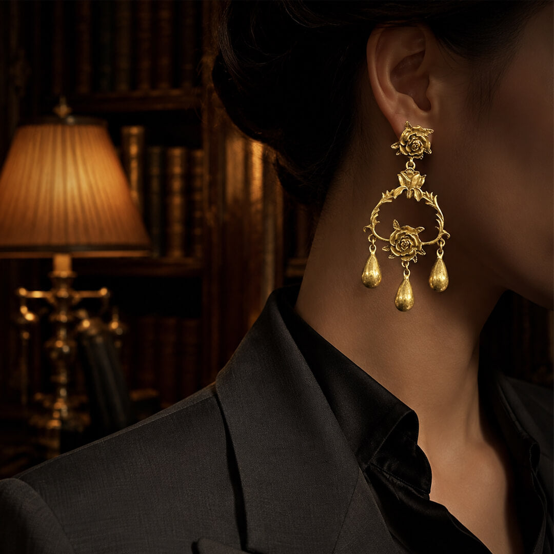 Close-up of vintage-style antiqued gold earrings featuring a 3D rose and thorny vine design.
