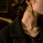 Close up of antique gold geometric earrings with purple crystal on brown velvet.