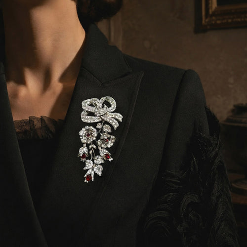 Elegant woman wearing the Duskcast Empress Bow crystal statement brooch on a black couture blazer.