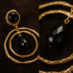Close up of textured gold double hoop earrings featuring a faceted black teardrop stone.
