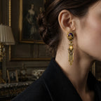 A full pair of vintage-style heavy gold dangle earrings featuring deep violet stones.