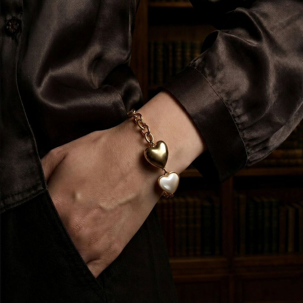 Elegant woman in a silk shirt wearing a heavyweight retro style gold heart bracelet.