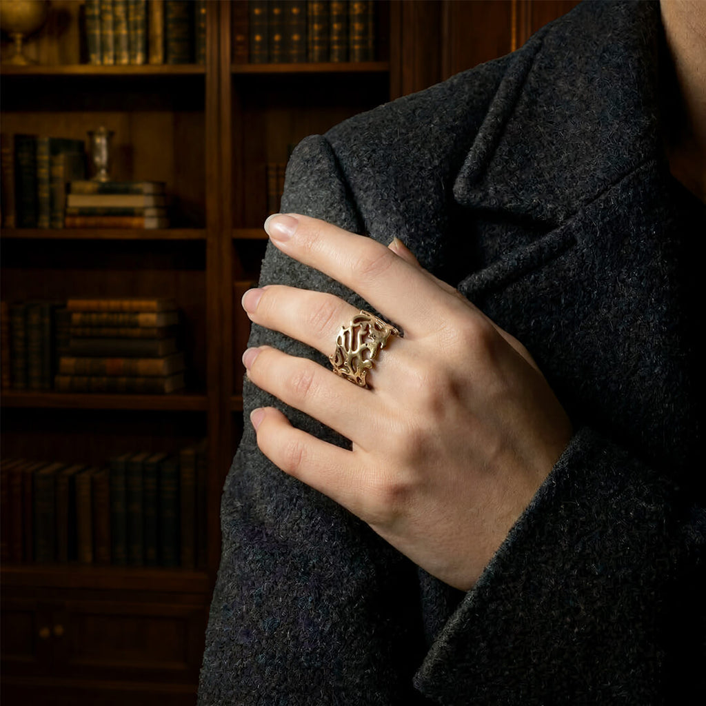 Close up of a woman wearing a heavy gold botanical statement ring.