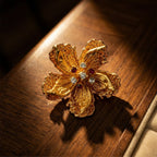 Retro Style gold alloy floral brooch with zircon accents on warm wood display
