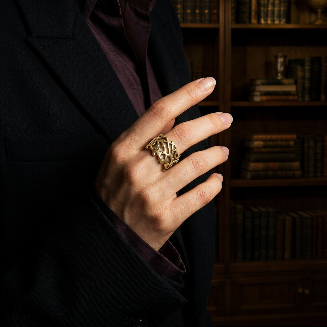 Woman wearing a dark blazer and a vintage-inspired gold cutout ring.