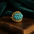 Vintage-Inspired turquoise cluster statement ring with a gold-tone setting on a dark vintage book.