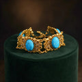 Vintage-Inspired turquoise filigree statement bracelet with gold-tone panels and faux pearl accents.