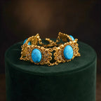 Vintage-Inspired turquoise filigree statement bracelet with gold-tone panels and faux pearl accents.