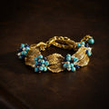 Vintage-Inspired turquoise leaf statement bracelet with gold-tone leaves and clustered blue beads.