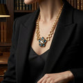 Alt Text: Model wearing a vintage-inspired chunky gold necklace with a large azure blue gemstone pendant, styled with a black tailored blazer for an Old Money aesthetic.
