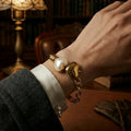 Woman wearing a vintage-inspired chunky gold twin heart bracelet under warm lamp light.